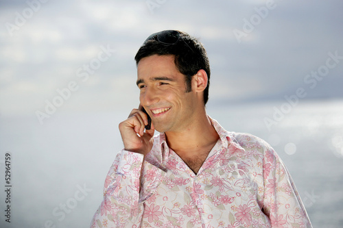 Photo: Smiling man on the phone by the coast Smiling man on the phone by the coast