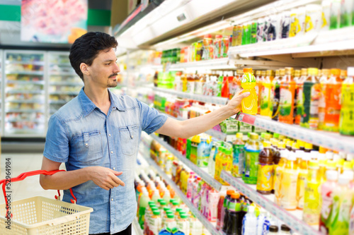 Photo: man in a supermarket buying a bottle of juice man in a supermarket buying a bottle of juice