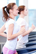 Two young sporty women run on machine