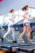 Two young sporty women run on machine