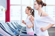 Two young sporty women run on machine