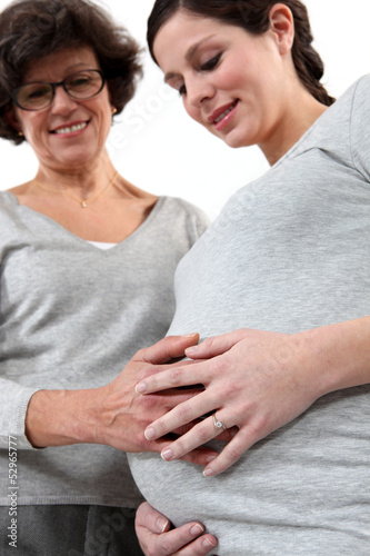 Photo: young pregnant woman and mother laying hand on her belly young pregnant woman and mother laying hand on her belly
