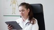 Female doctor with tablet computer in her office, tracking shot