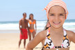 Photo: Young girl at the beach with her parents Young girl at the beach with her parents