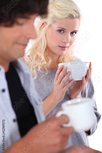 Photo: Young woman holding a bowl with man in the foreground Young woman holding a bowl with man in the foreground