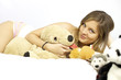 Cute blond woman in bed laying with many stuffed toys