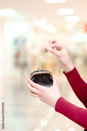 Photo: Hands holding coin and retro styled money pouch in mall Hands holding coin and retro styled money pouch in mall