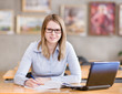 female student with laptop working in library. looking at camera