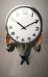 man holds a clock hiding her face