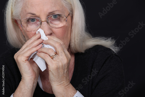 Photo: Elderly woman blowing her nose Elderly woman blowing her nose