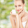 Cute woman applying cream to her face