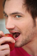 Young man biting into red apple