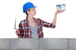 Photo: Female construction worker with a house made of money Female construction worker with a house made of money