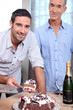 Two men cutting celebration cake