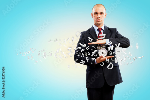 Photo: Business man holding alarmclock Business man holding alarmclock