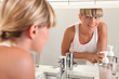 Photo: Young woman looking in the bathroom mirror Young woman looking in the bathroom mirror