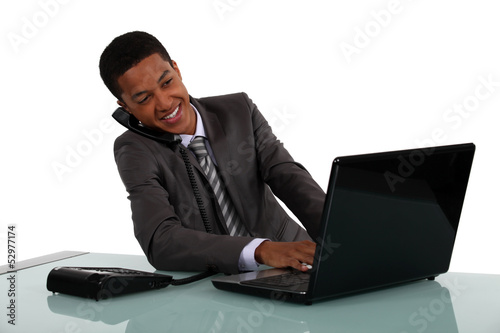 Photo: Businessman typing whilst on telephone call Businessman typing whilst on telephone call