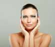 Happy woman touching her face isolated on grey background