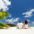 Happy couple sitting on the sunny beach