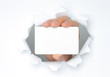 Photo: Hand holds white card through white torn paper . Hand holds white card through white torn paper .