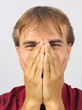man covers his face with two hands