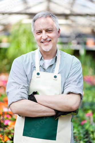 Photo: Mature gardener in a greenhouse Mature gardener in a greenhouse