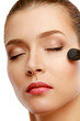 Beautiful young adult woman applying cosmetic paint brush