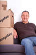Man sitting on the sofa next to his moving boxes