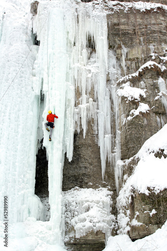 Photo: Ice climber struggles up a frozen waterfall. Ice climber struggles up a frozen waterfall.