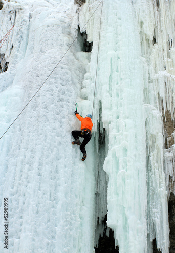 Photo: Ice climber struggles up a frozen waterfall. Ice climber struggles up a frozen waterfall.