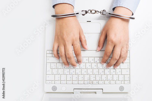 Photo: Female hands in handcuffs, with laptop Female hands in handcuffs, with laptop