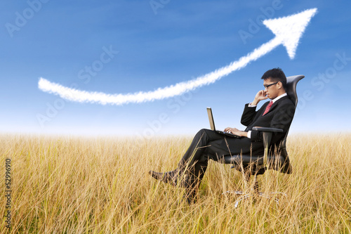 Photo: Businessman sit outdoor with success arrow sign Businessman sit outdoor with success arrow sign