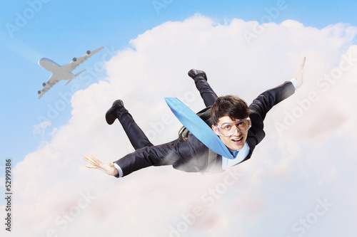 Photo: Young businessman flying with parachute on back Young businessman flying with parachute on back