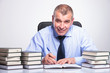 Photo: old business man writes at desk full of books old business man writes at desk full of books