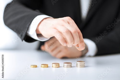 Photo: man putting stack of coins into one row man putting stack of coins into one row