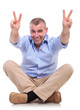casual middle aged man sits and shows victory