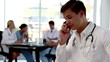Focus on a doctor phoning besides colleagues
