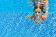 Happy active child swims underwater in pool