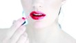 Attractive woman putting lipstick on her lips