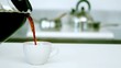 Black coffee being poured into cup of coffee