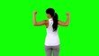 Woman in sportswear tensing her arms on green screen