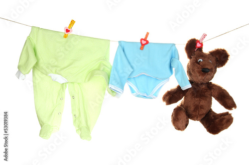 Photo: Baby clothes hanging on clothesline, isolated on white Baby clothes hanging on clothesline, isolated on white