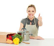 Woman in apron sitting  with grocery bag and showing ok