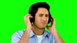 Man listening to music with headphones on green screen