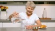 Happy woman pouring a glass of water for breakfast