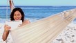 Smiling woman using tablet in a hammock