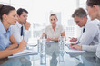 Businesswoman looking at camera with colleagues working around