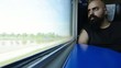 bearded man looking out the window of speeding train