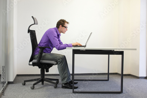 Photo: shortsighted businessman bad sitting posture at laptop shortsighted businessman bad sitting posture at laptop