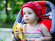 baby sitting in a pram eating banana